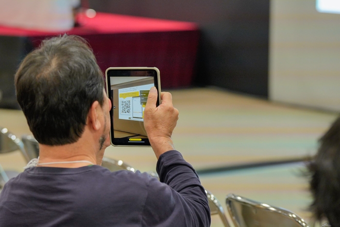 質問用チャットにアクセスするためのQRコードを読み込む観客